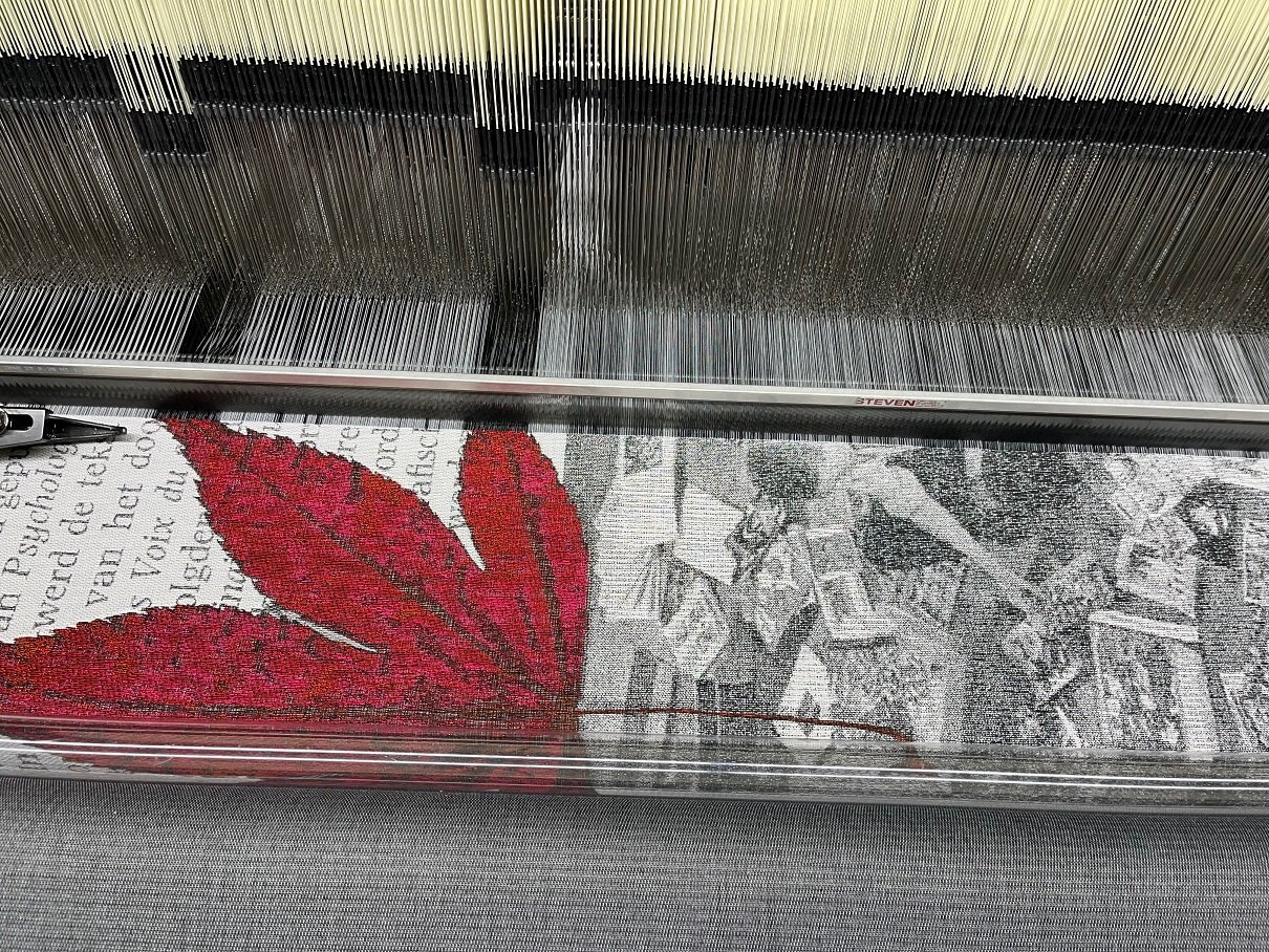 Detailansicht auf einen Webstuhl mit gewebtem schwarz weiss Sujet mit einer roten Blume