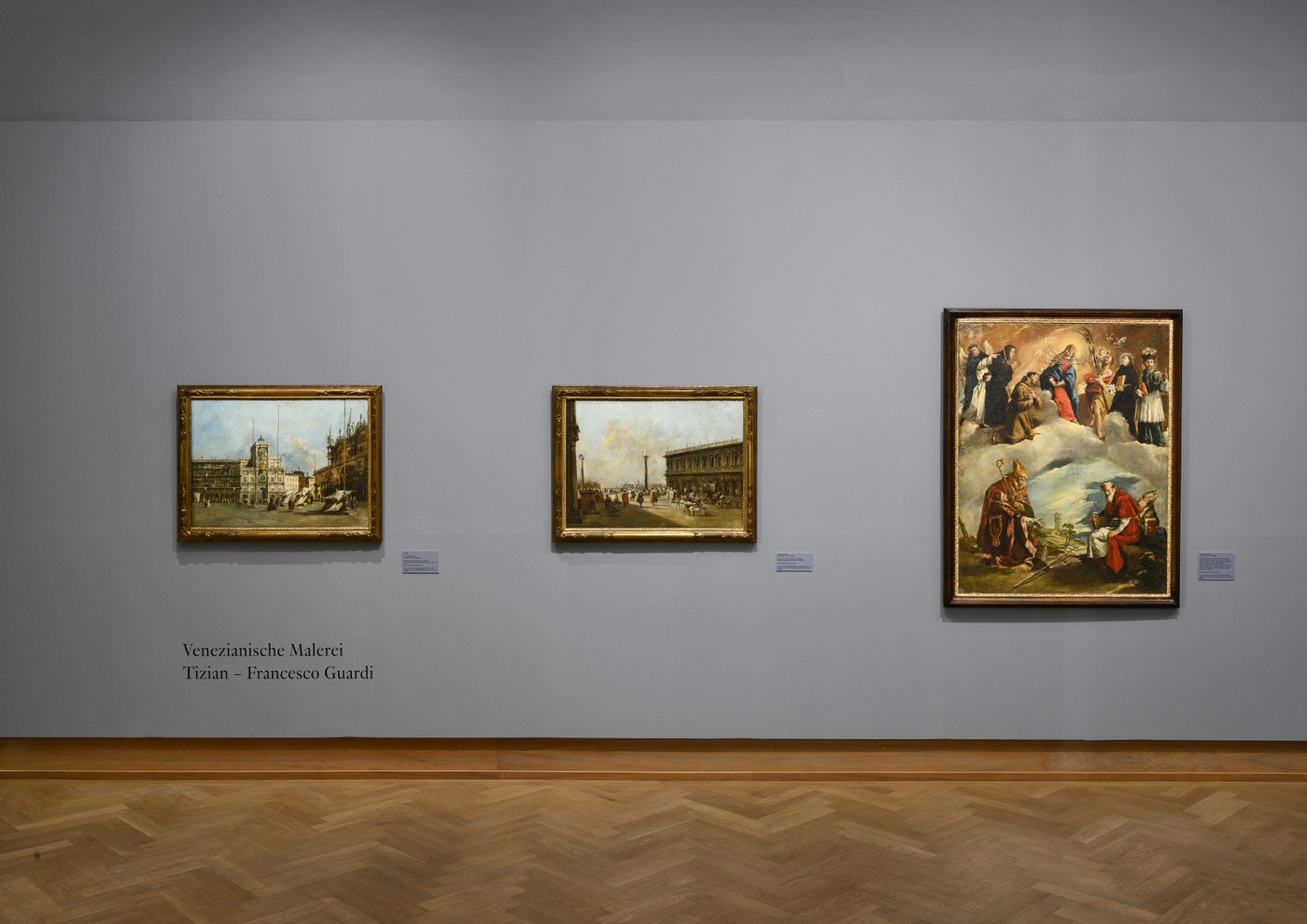 Ein blau ausgemalter Ausstellungsraum mit gerahmten Gemälden an der Wand