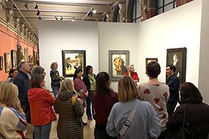 eine Menschengruppe vor Bildern in einer Ausstellungsführung