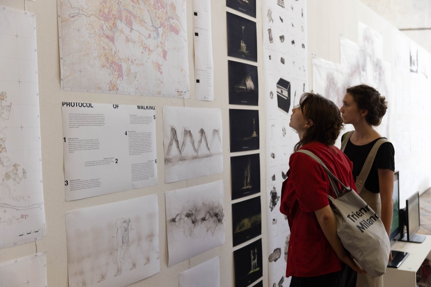 Personen besichtigen die Ausstellungsobjekte, mehrere Stadtpläne an eine Stellwand genagelt