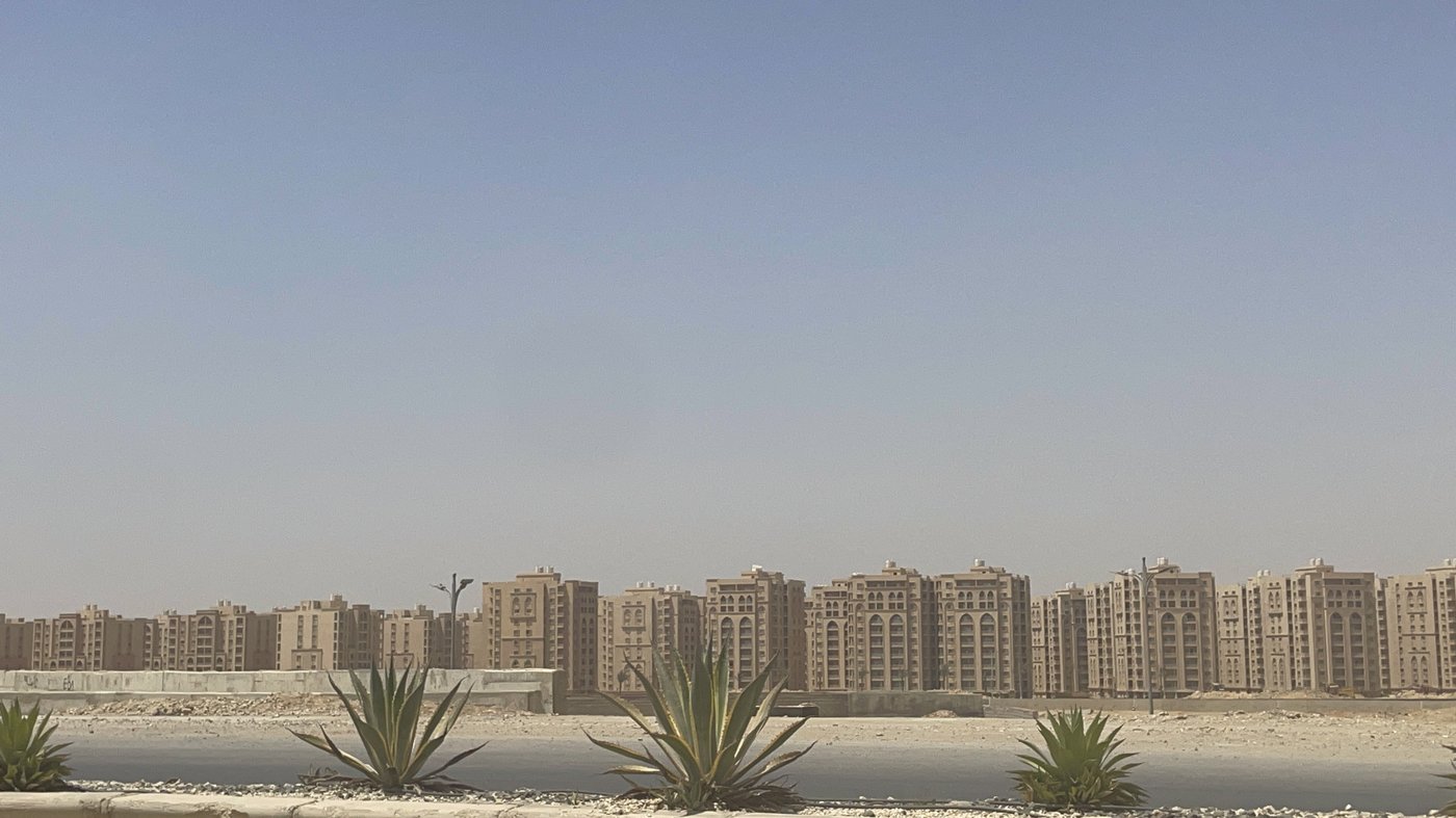 Augnahme einer langen Reihe von neugebauten, noch unbewohnten braunen uniformen Häusern, rundherum nur Sand