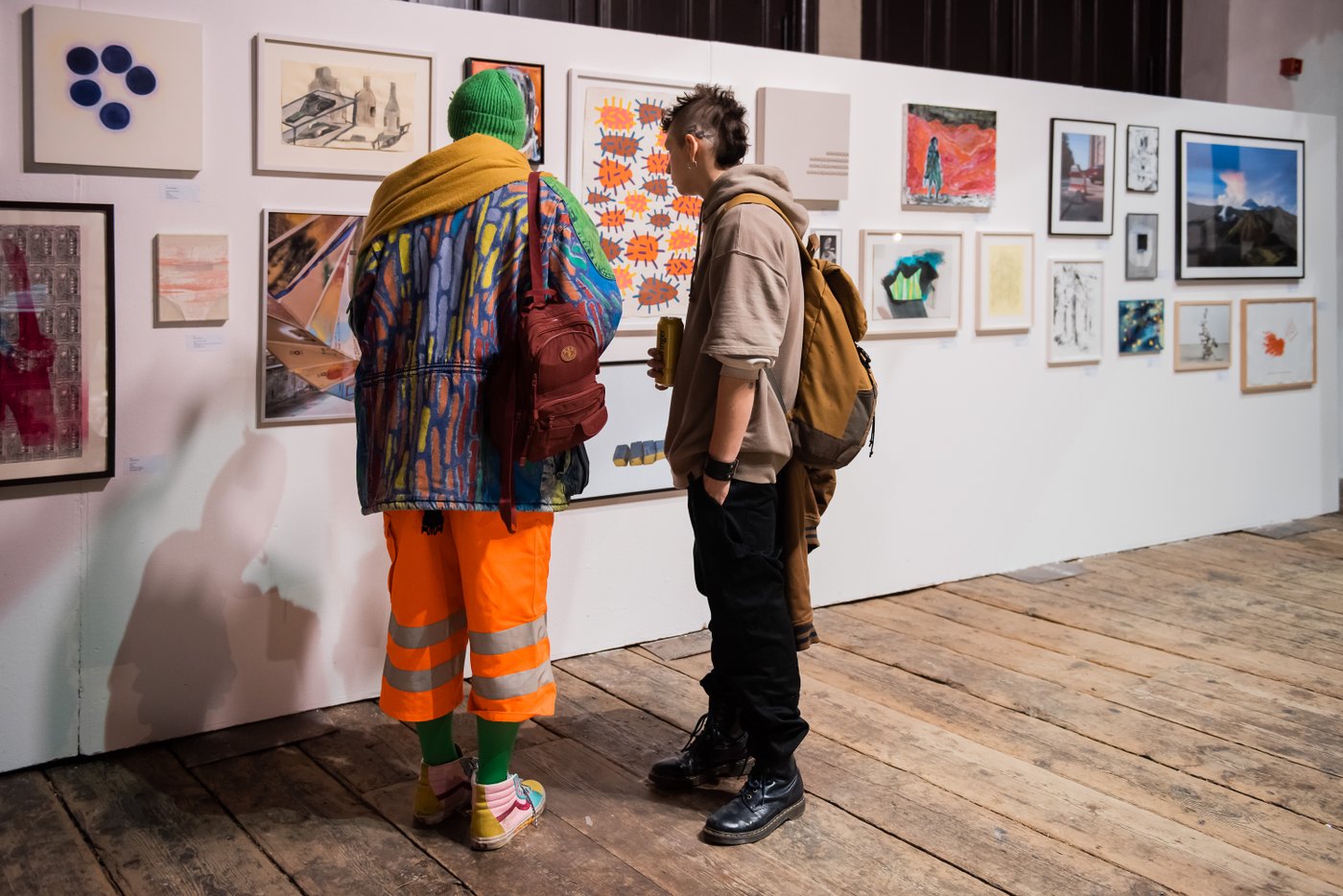 Personen schauen sich Kunstwerke an einer Wand an