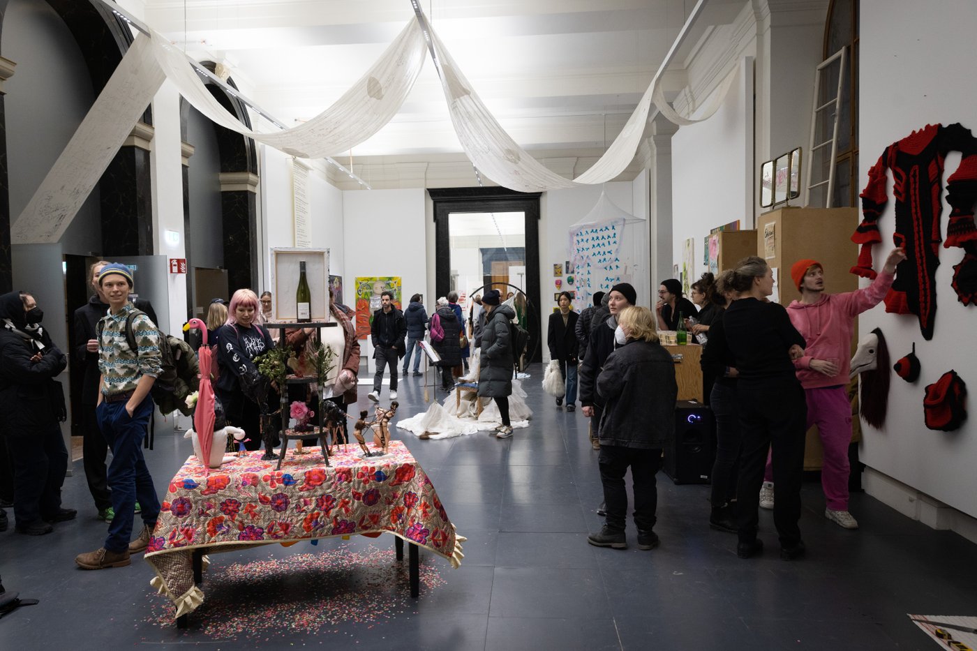 Gruppe von Menschen in einem Raum die miteinander Reden und Kunstwerke ansehen
