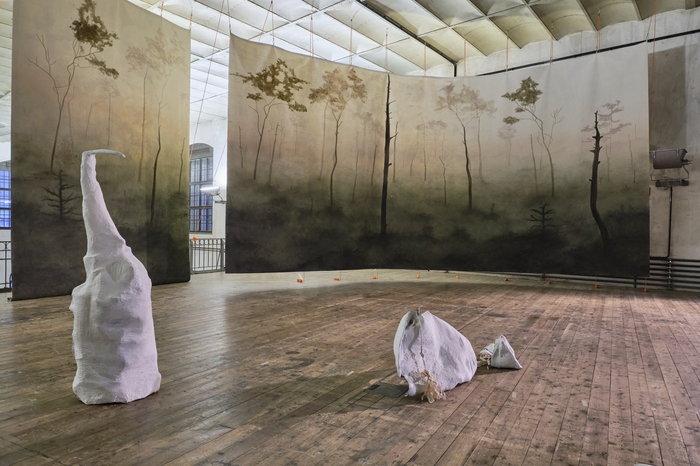 Diploma performance with painted prospectus, 2022, photo © Lab_tf In the background you can see brochures painted with a light forest scene, in front of them are 2 white amorphous sculptures on the wooden floor.
