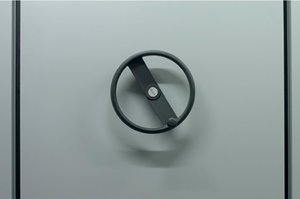 A section of an archive shelf, you can see the gray side wall and a black wheel with which the shelf can be moved.