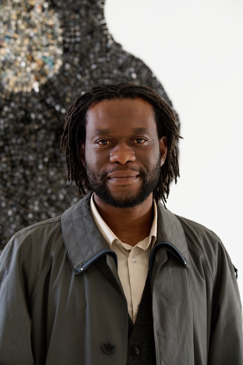 Portrait of the Artist Moffat Takadiwa in front of an artwork