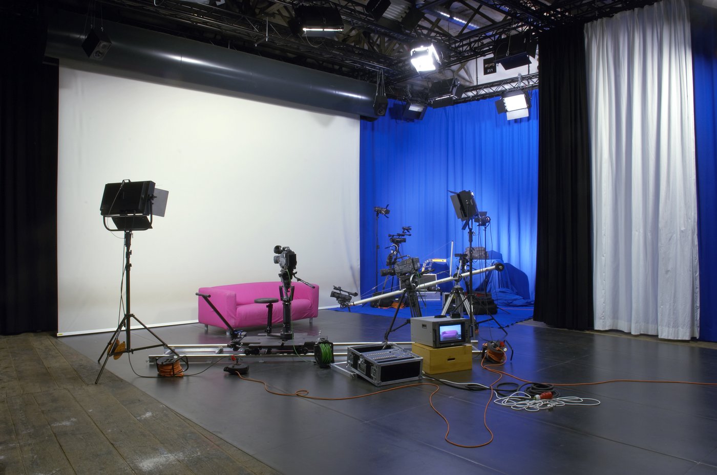 View into the video studio of the academy, photo © Lisa Rastl A typical video studio with a variety of cameras, monitors and other equipment. A pink sofa, on the back wall a blue curtain.